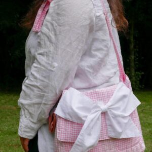 femme qui porte un sac bandoulière rose et blanc à carreaux avec un gros nœud